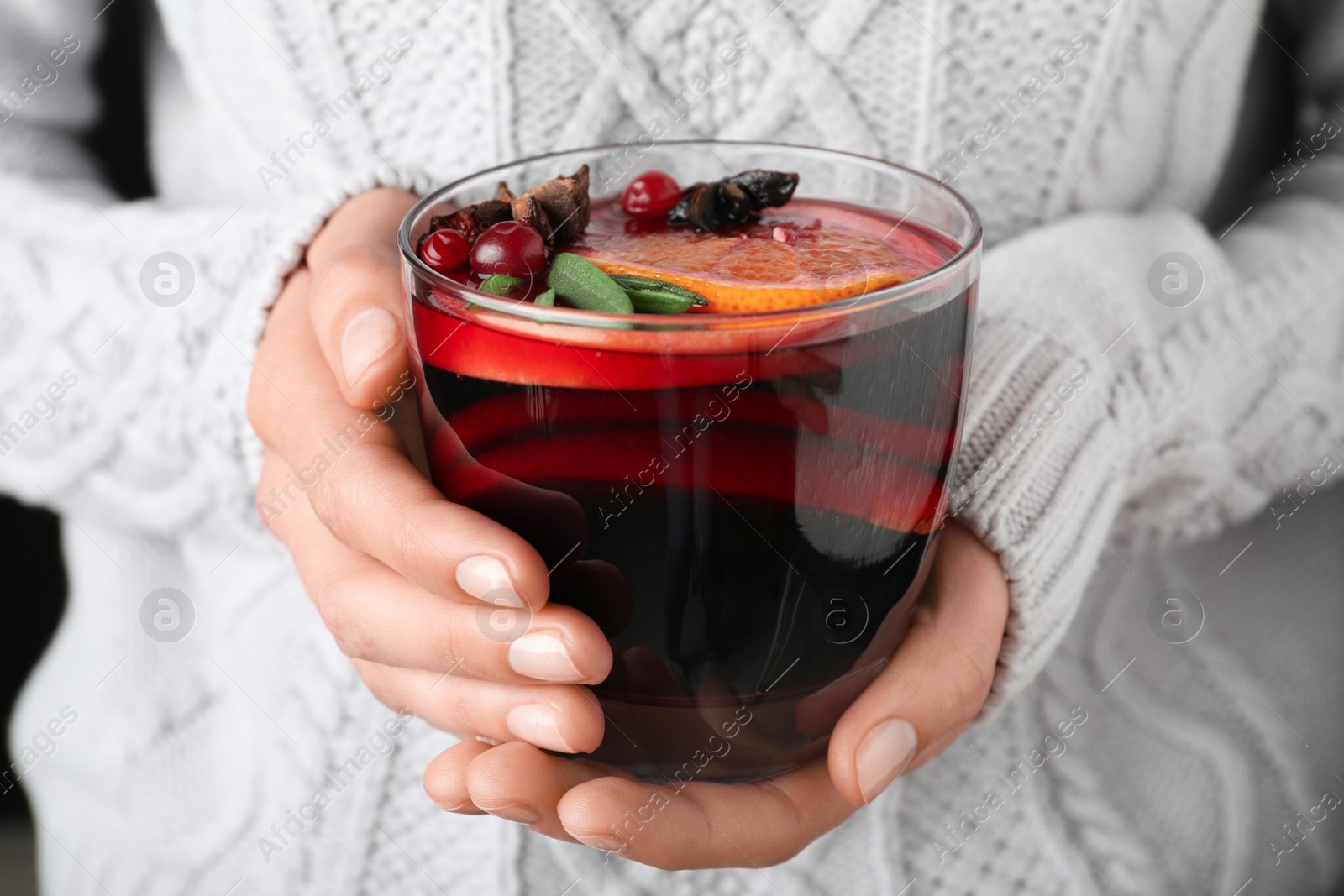 Photo of Woman holding glass cup of tasty mulled wine, closeup