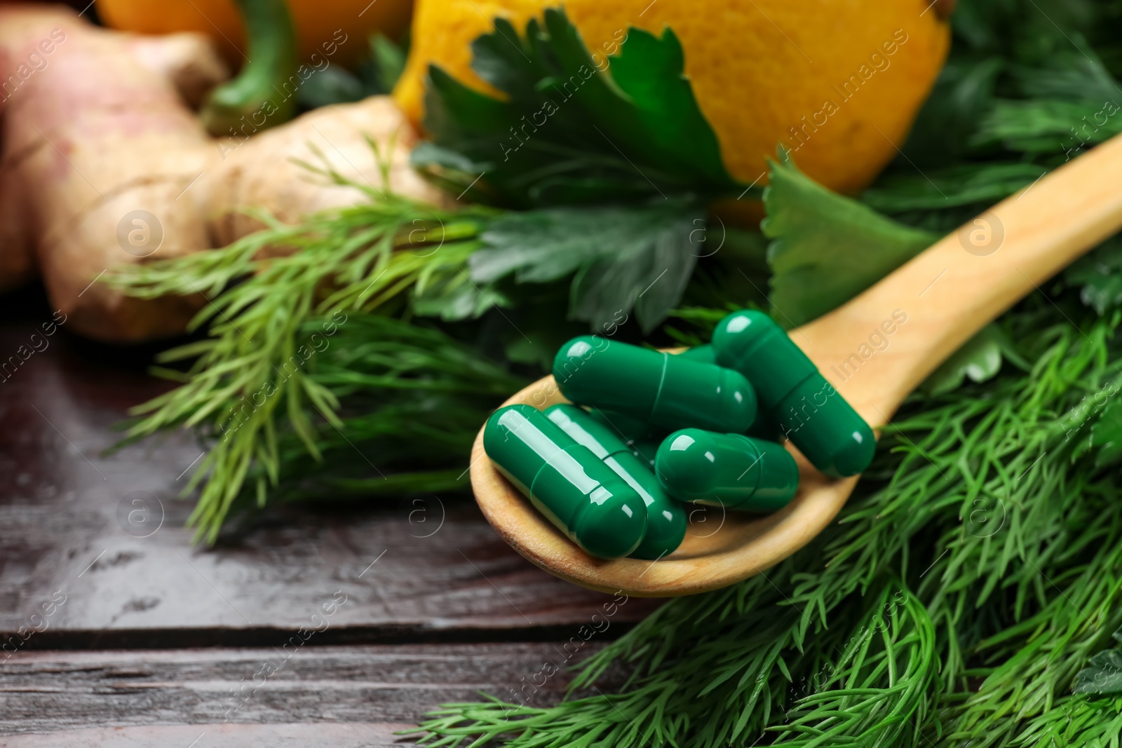 Photo of Dietary supplements. Spoon with pills and food products on wooden table, closeup