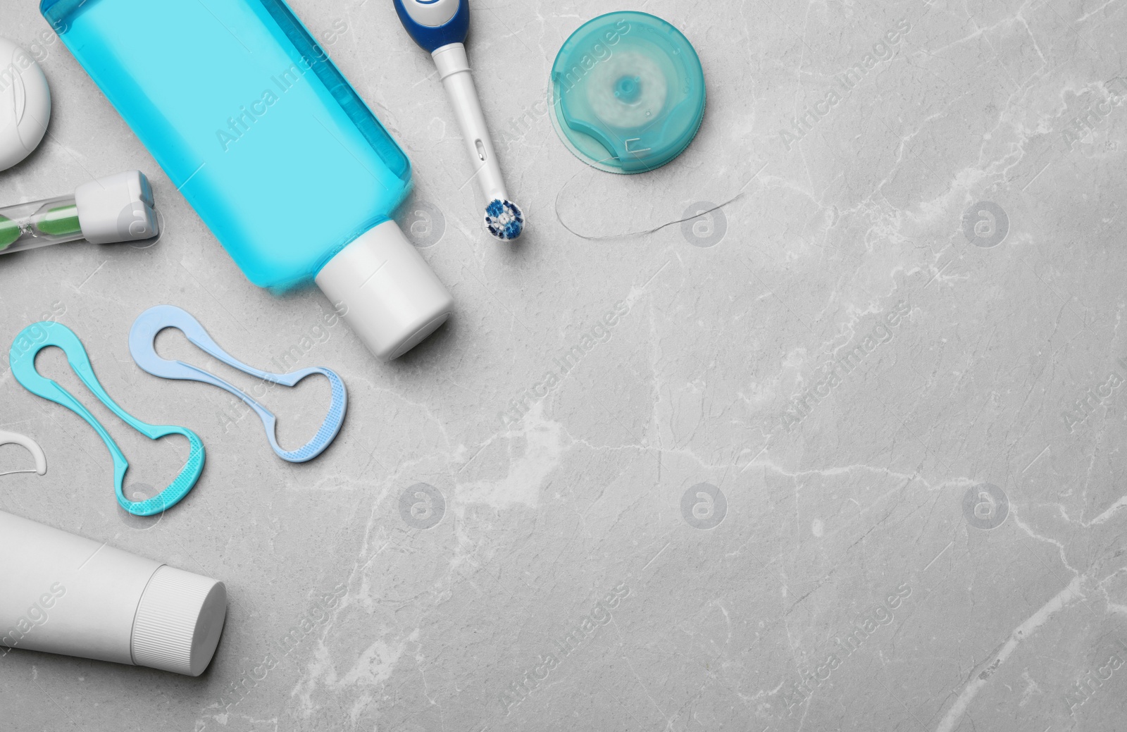Photo of Flat lay composition with tongue cleaners and teeth care products on grey background. Space for text