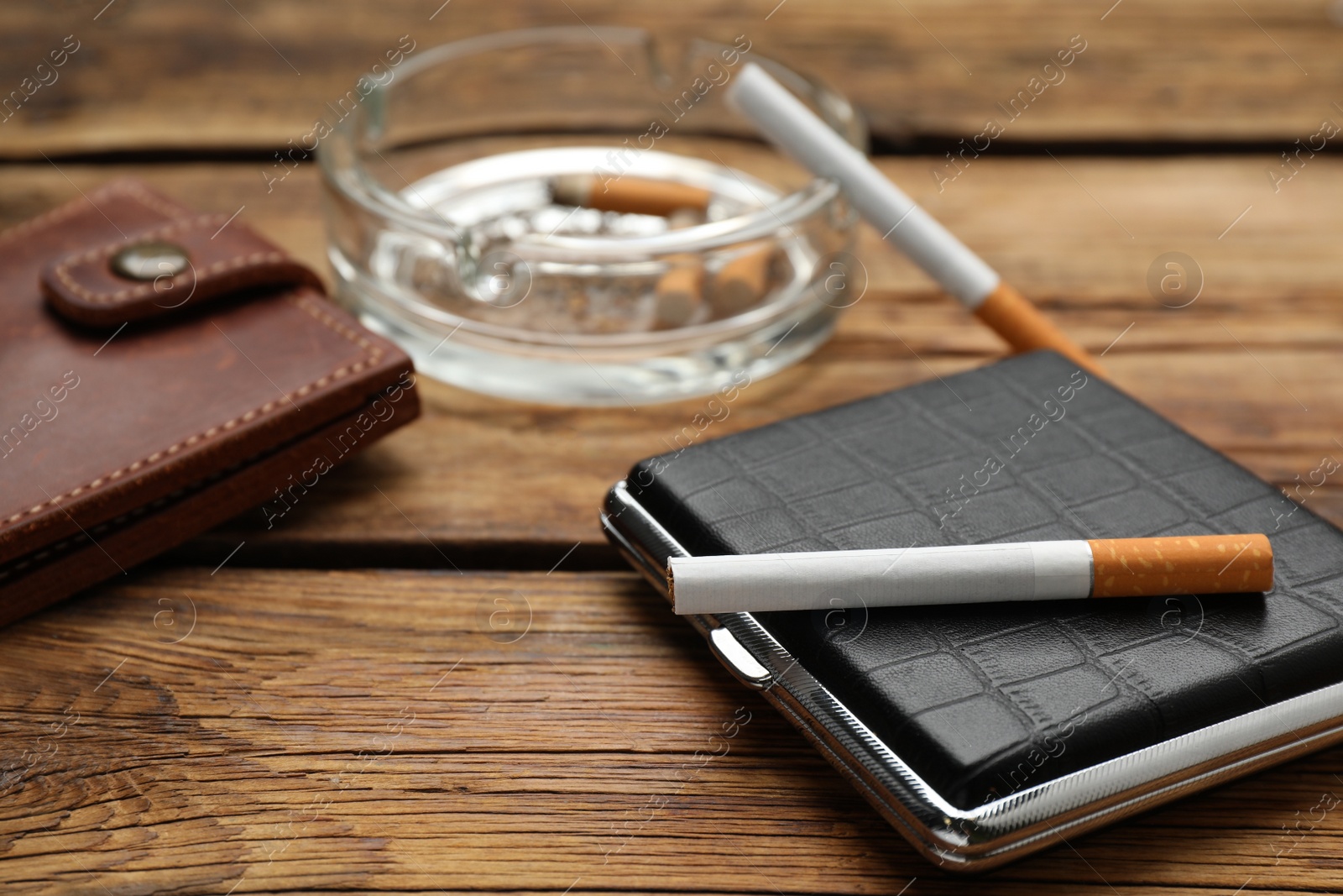Photo of Stylish leather case with cigarette on wooden table. Space for text