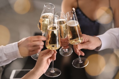 Photo of Friends clinking glasses of champagne in restaurant, closeup