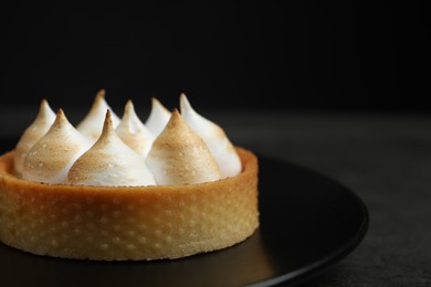 Photo of Tartlet with meringue on black table, closeup and space for text. Delicious dessert