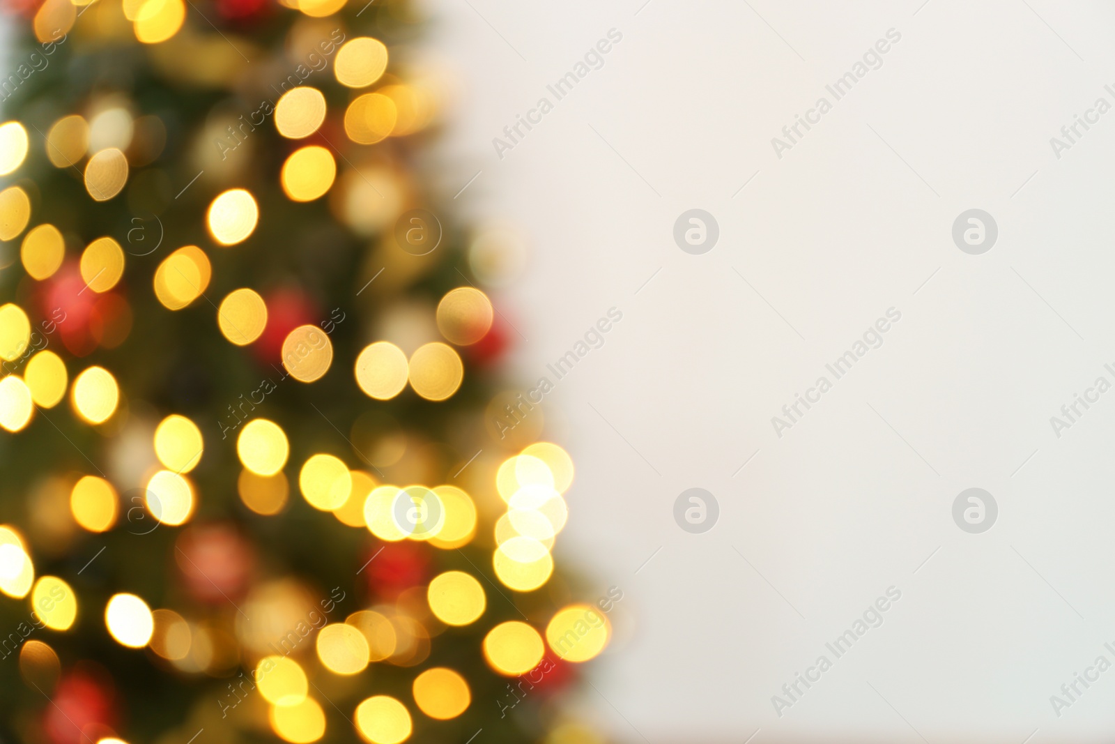 Photo of Blurred view of Christmas tree with fairy lights on white background