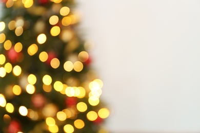 Blurred view of Christmas tree with fairy lights on white background