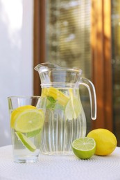 Photo of Water with lemons and limes on white table outdoors