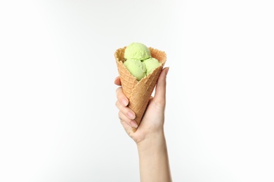 Woman holding delicious ice cream in waffle cone on white background, closeup