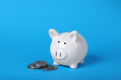 Photo of Ceramic piggy bank and coins on light blue background. Financial savings