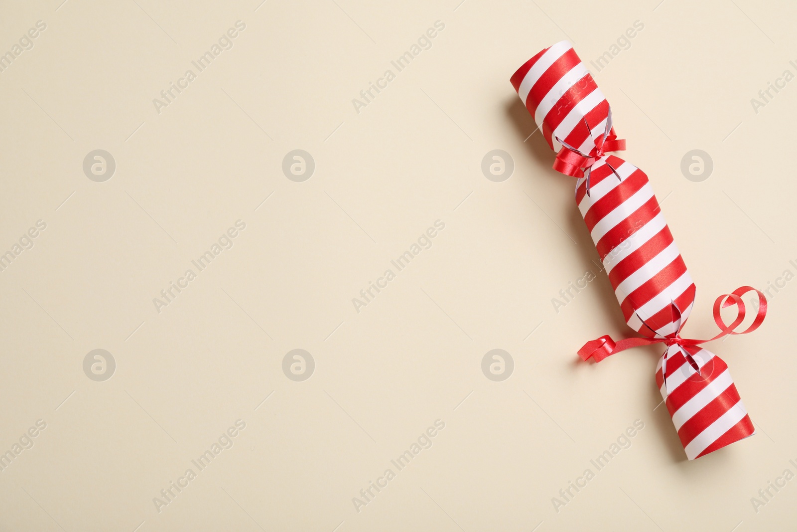 Photo of Christmas cracker on beige background, top view. Space for text