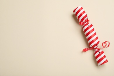 Photo of Christmas cracker on beige background, top view. Space for text