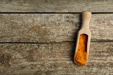 Photo of Scoop with saffron powder on wooden table, top view. Space for text