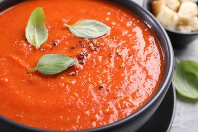 Photo of Delicious tomato cream soup served on grey table, closeup