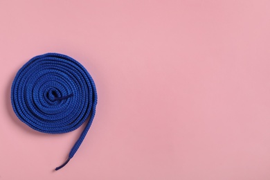 Photo of Blue shoelace on pink background, top view. Space for text