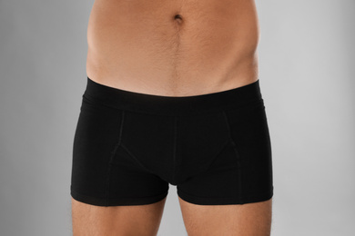 Man in black underwear on light grey background, closeup