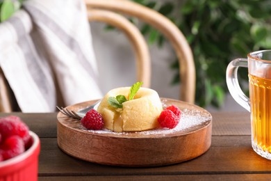 Tasty vanilla fondant with white chocolate and raspberries on wooden table