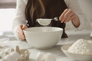 Woman making dough at table in kitchen, closeup