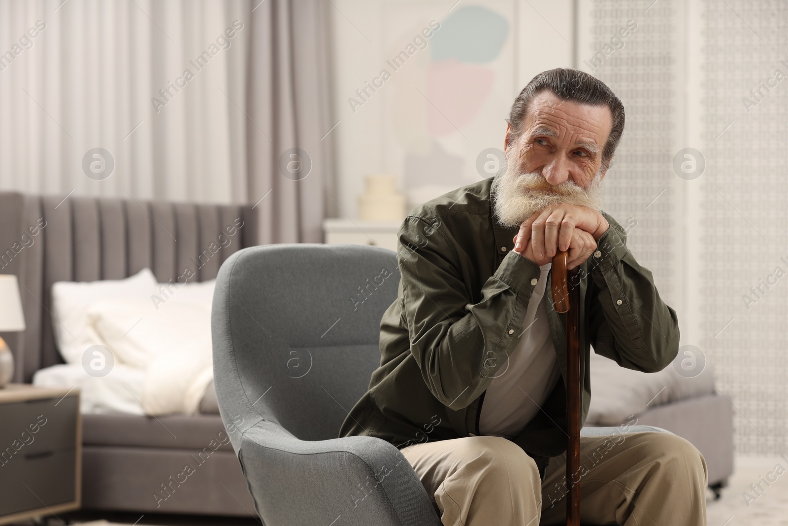 Photo of Senior man with walking cane in armchair at home