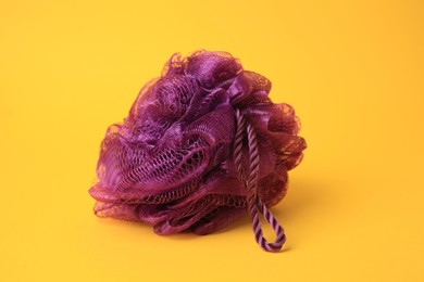 Photo of Purple shower puff on yellow background. Personal hygiene