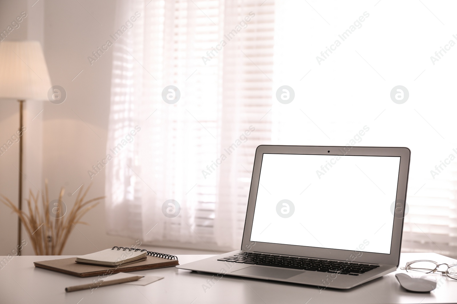 Photo of Laptop on desk near window in office. Comfortable workplace