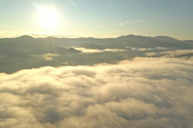 Photo of Aerial view of beautiful mountains covered with fluffy clouds on sunny day