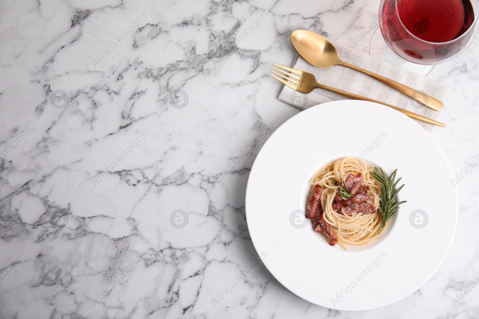 Photo of Delicious Carbonara pasta served on white marble table, flat lay. Space for text