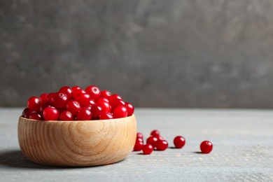 Tasty ripe cranberries on grey wooden table, closeup. Space for text