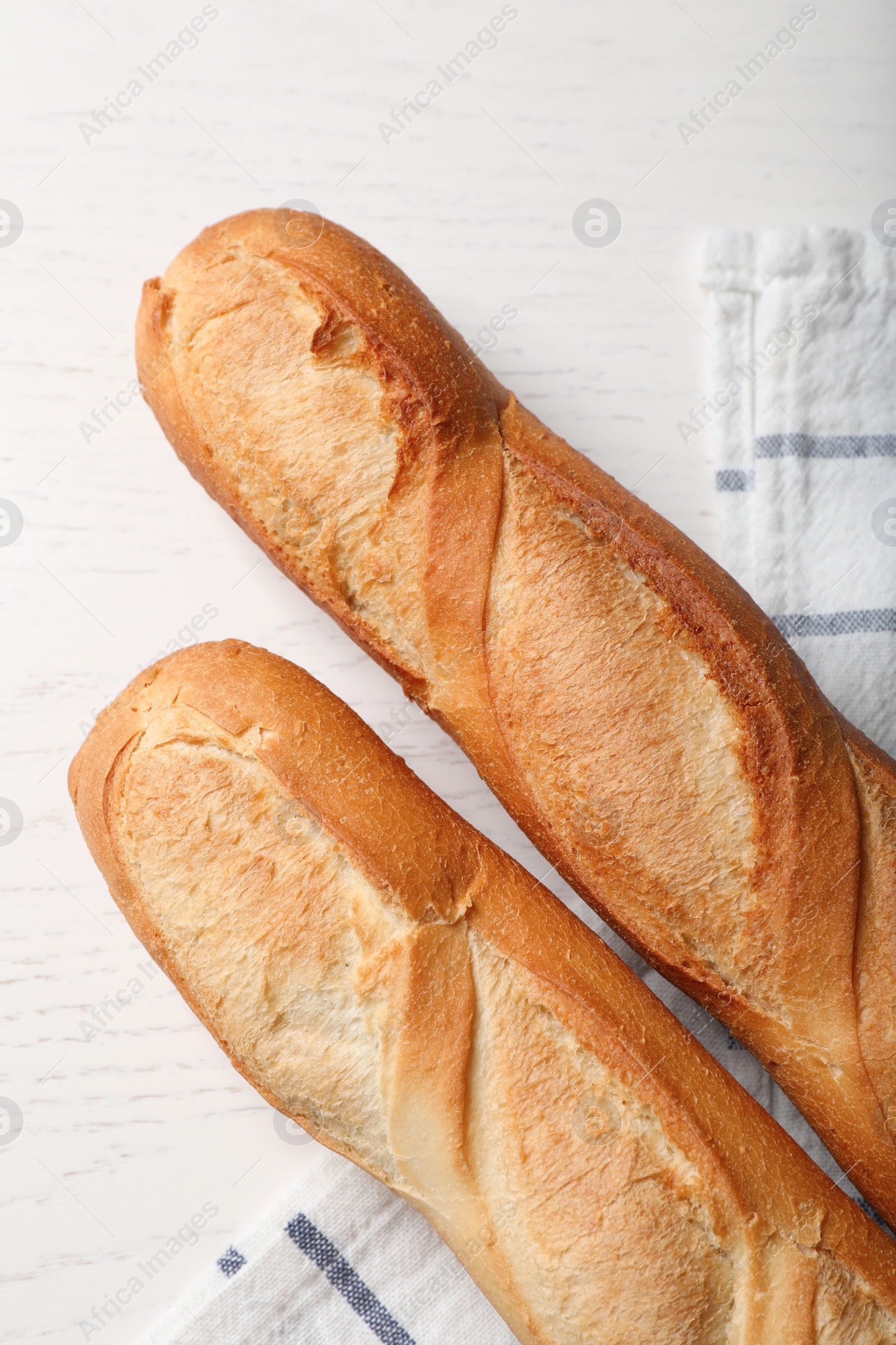 Photo of Tasty baguettes on white wooden table, flat lay