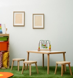 Stylish playroom interior with table and stools