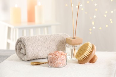 Photo of Spa composition. Sea salt, brush, towel and reed air freshener on soft surface