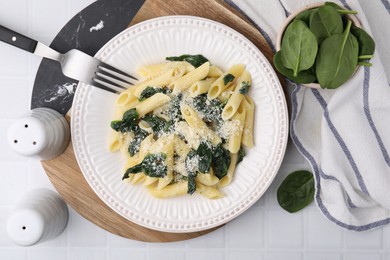 Photo of Tasty pasta with spinach and cheese served on white tiled table, flat lay