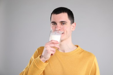 Milk mustache left after dairy product. Man drinking milk on gray background