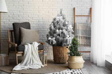Stylish interior with beautiful Christmas tree near white brick wall