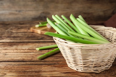 Fresh lemongrass in wicker bowl on wooden table, space for text