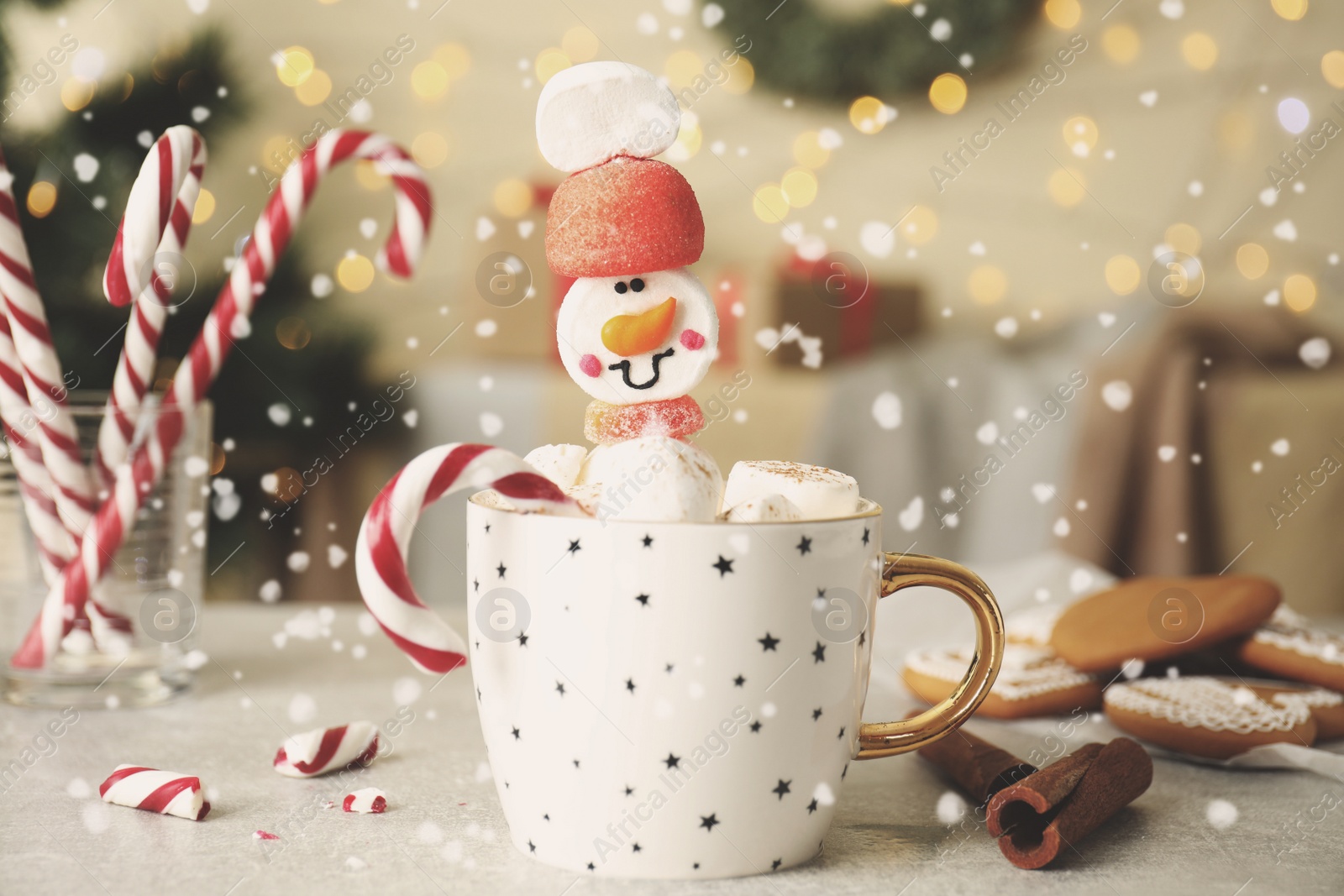 Photo of Funny marshmallow snowman in cup of hot drink on light grey table