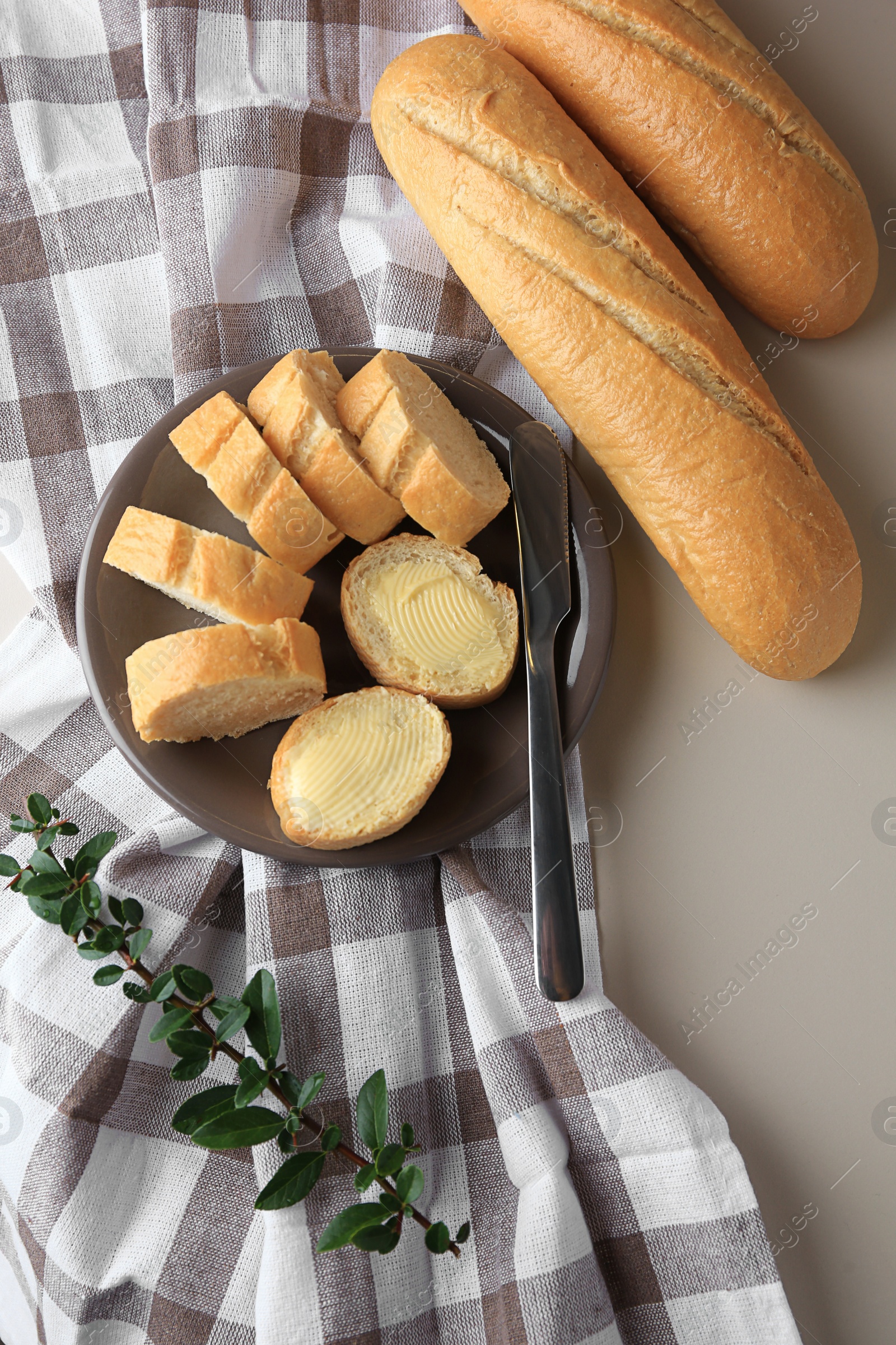 Photo of Whole and cut baguettes with fresh butter on table, flat lay