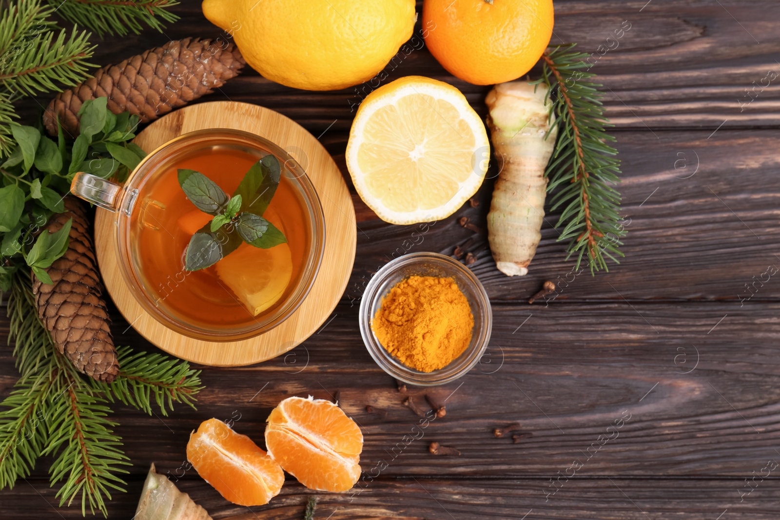 Photo of Glass cup of delicious immunity boosting tea with ingredients on wooden table, flat lay. Space for text