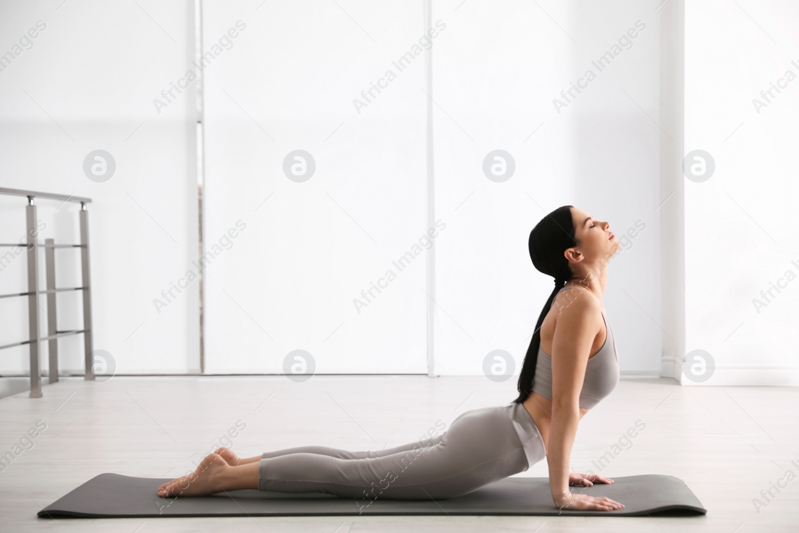 Photo of Young woman practicing cobra asana in yoga studio. Bhujangasana pose