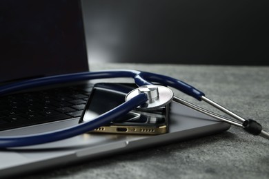 Modern electronic devices and stethoscope on grey table, closeup