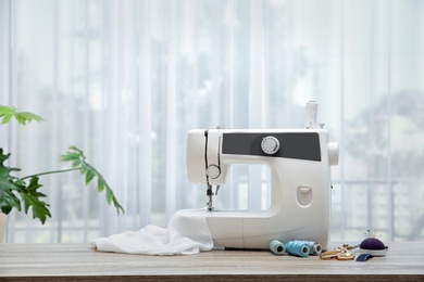 Photo of Sewing machine on table near window indoors