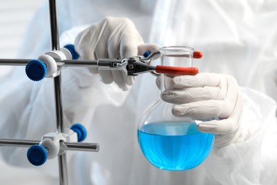 Scientist working with flask of light blue liquid, closeup