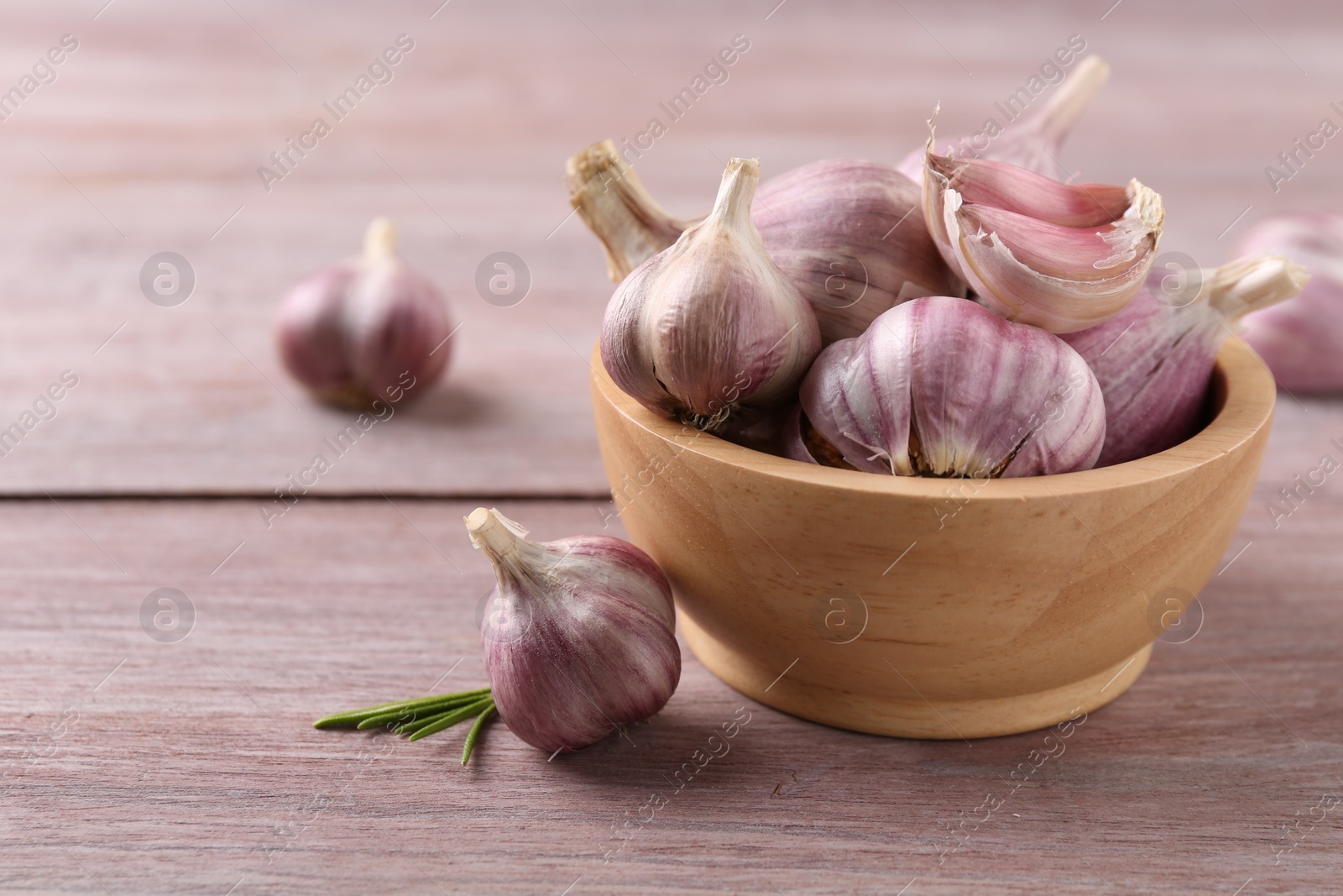 Photo of Bowl with fresh garlic on wooden table, closeup. Space for text