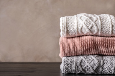 Photo of Stack of folded knitted sweaters on table. Space for text