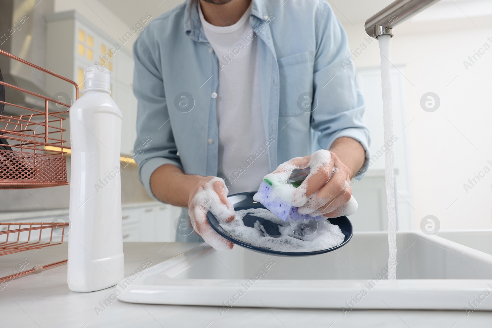 Photo of Man washing plate above sink in kitchen, closeup