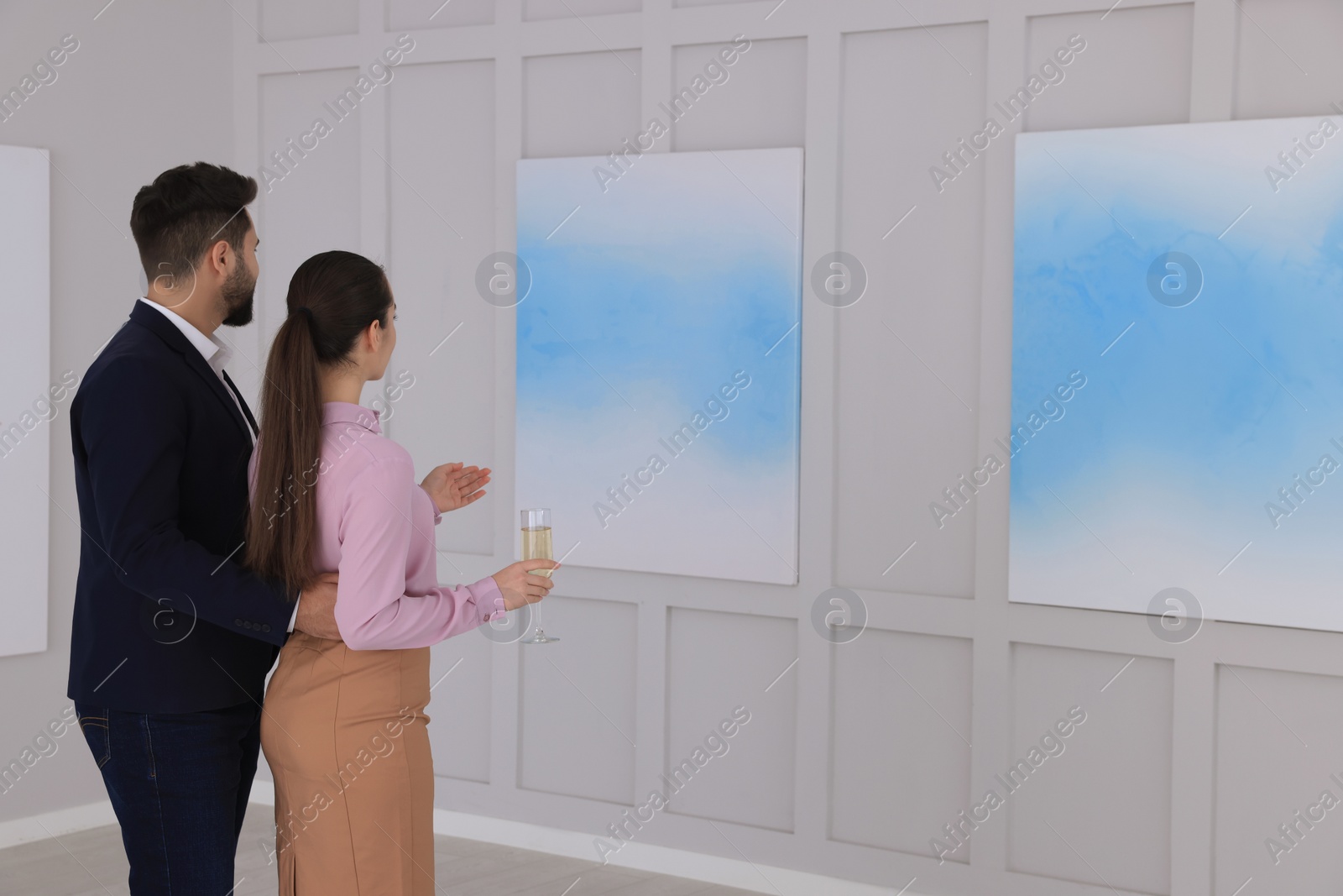 Photo of Young couple with glass of champagne at exhibition in art gallery