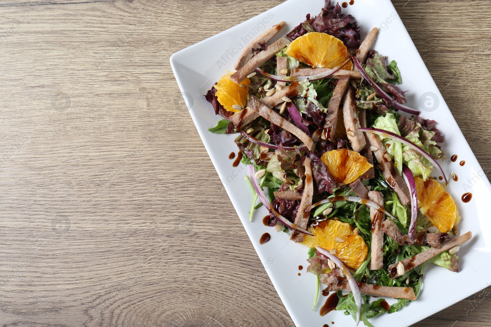 Photo of Delicious salad with beef tongue, orange and onion on wooden table, top view. Space for text