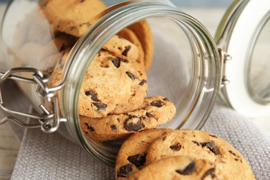 Jar of tasty chocolate chip cookies on table