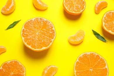 Photo of Flat lay composition with halves of fresh ripe tangerines and leaves on yellow background. Citrus fruit