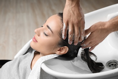 Photo of Stylist washing client's hair at sink in beauty salon