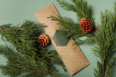 Photo of Scented sachet, pine cones and fir branches on green background, flat lay
