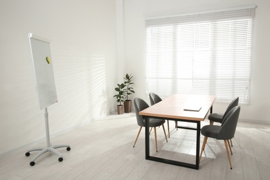 Photo of Conference room interior with wooden table and flipchart