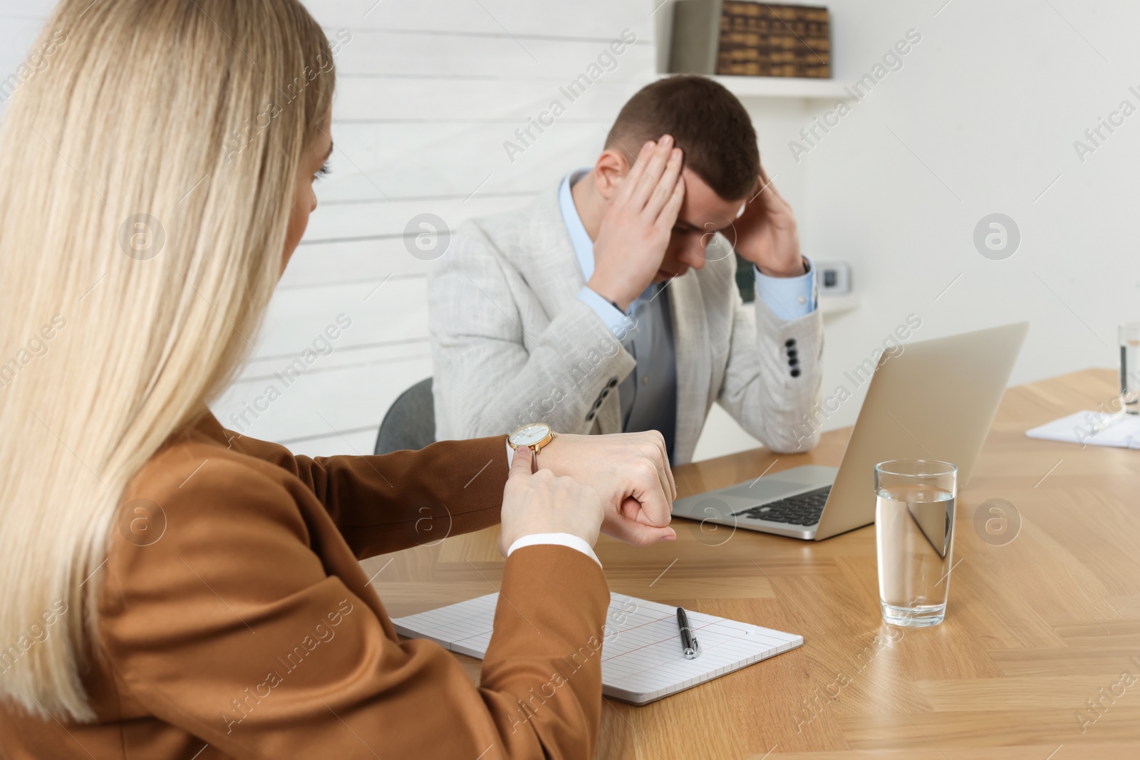 Photo of Businesswoman pointing on wrist watch while scolding employee for being late in office